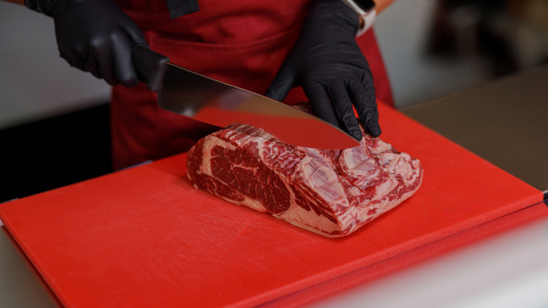 person cutting on a red cutting board