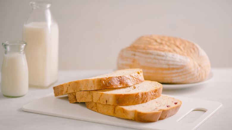 bread on a white cutting board with dairy nearby