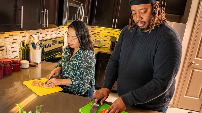man and woman prepping food on yellow and green cutting boards
