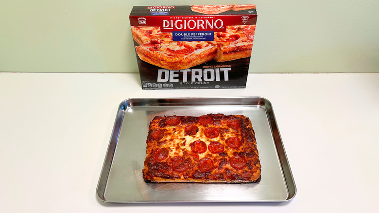 A box of DiGiorno Double Pepperoni Detroit Style Pizza next to a silver pan of deep dish pizza