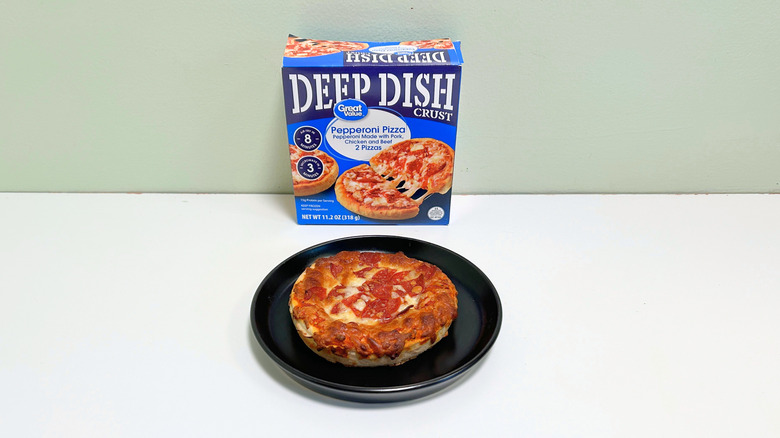 A box of Great Value Pepperoni Deep Dish Pizza next to a black plate of deep dish pizza