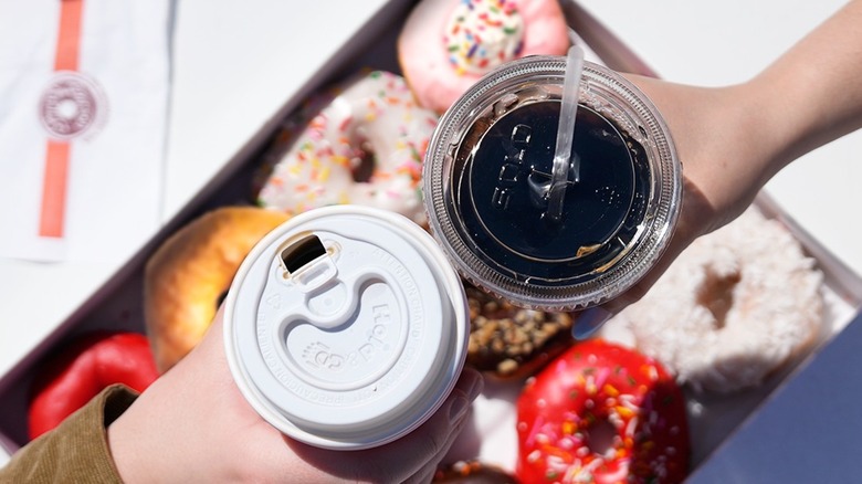 Hot & iced coffees toasting over a box of donuts
