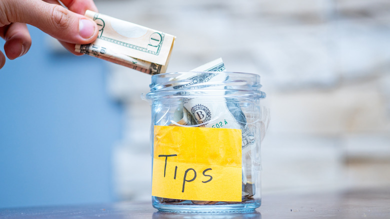 Hand putting bill in tip jar