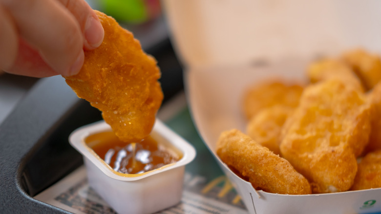Hand dipping nugget into dipping sauce