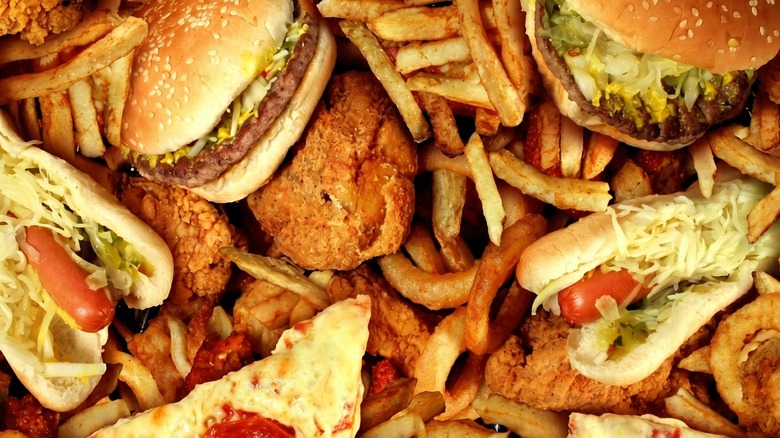 Pile of assorted fast foods, including burgers, hot dogs, and fries