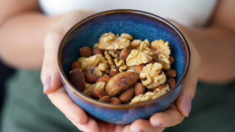 A close-up of a woman holding a bowl of nuts