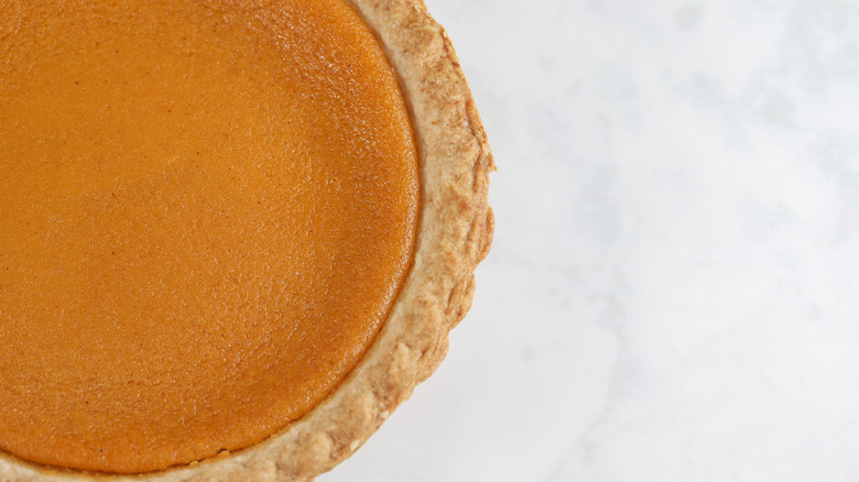 Whole sweet potato pie on a marble background