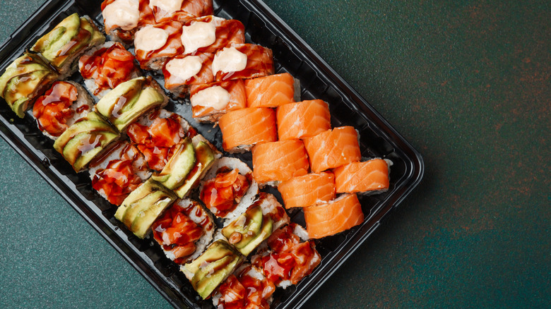 An overhead view of sushi in a black plastic container