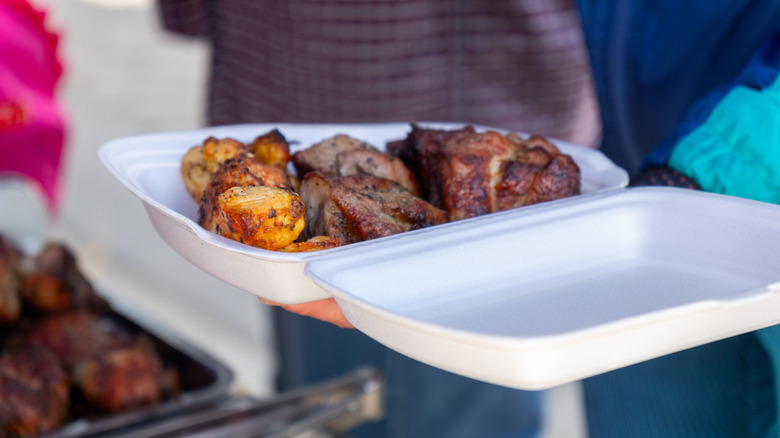 A Styrofoam container, with grilled meats inside