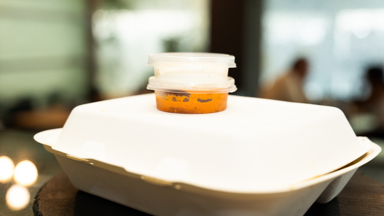 Takeout containers with sauce tubs balanced on top