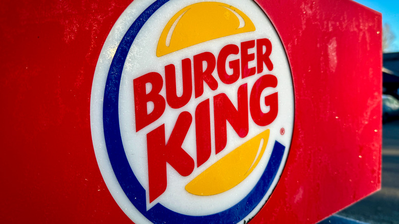 The circular Burger King logo that was in use throughout the 2000s and 2010s on a red sign outdoors