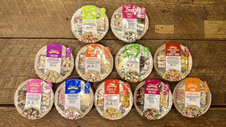 11 prepackaged Wegmans salads on a wooden salad