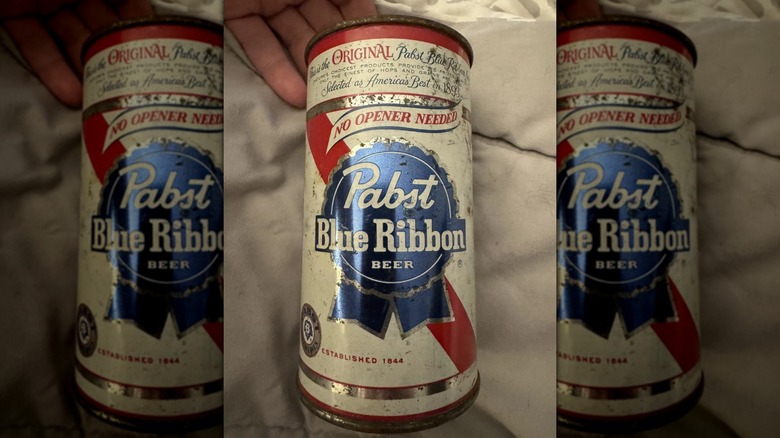 A Pabst Blue Ribbon can lying on a blanket