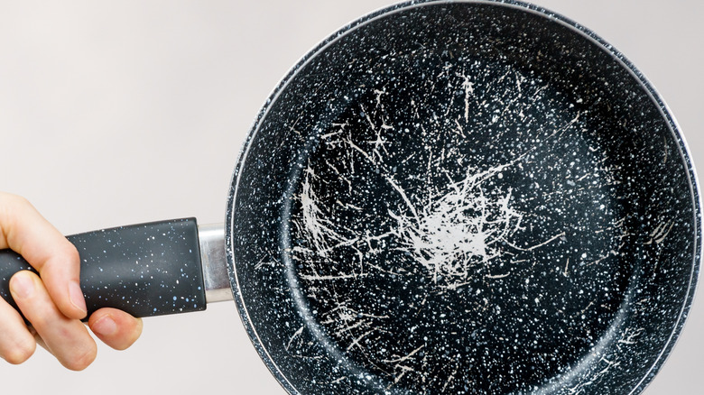 Hand holding scratched skillet