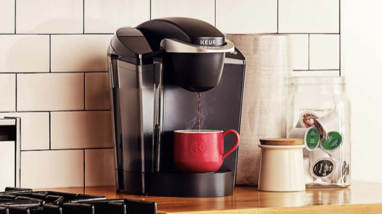 Keurig K-Classic coffee maker pouring coffee into red coffee mug