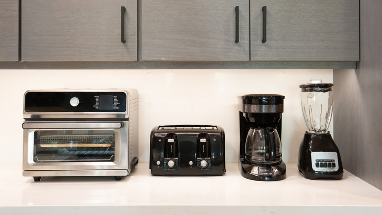 A toaster, toaster oven, coffee maker, and blender on a kitchen counter
