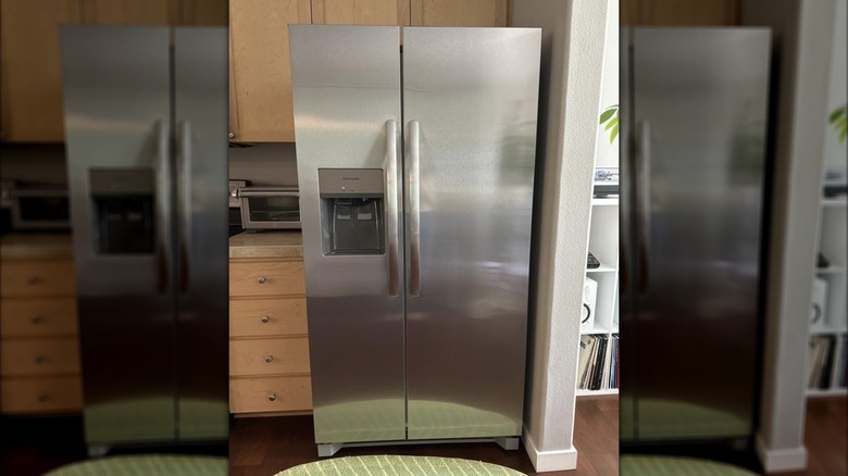 A stainless steel refrigerator with vertical doors and an ice maker/water station on the freezer door