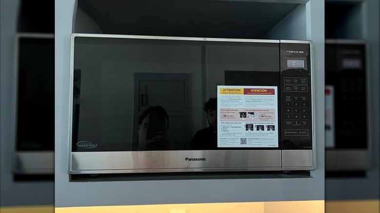 A large stainless steel Panasonic microwave inside a gray cabinet