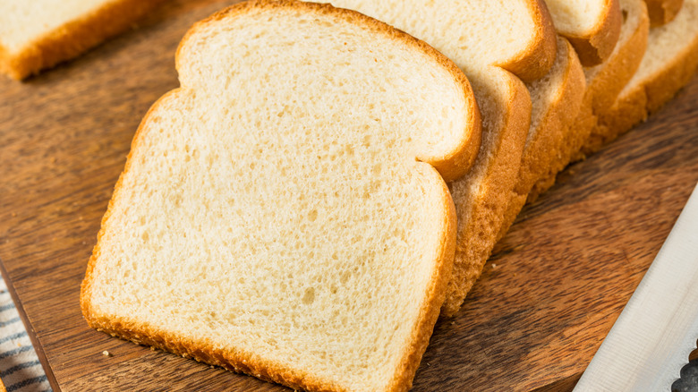 Sliced loaf of white bread laid out on cutting board