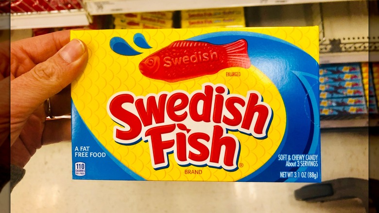 A hand holding a box of Swedish Fish in a store