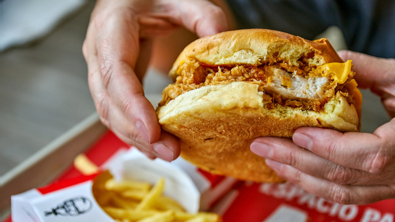 Hand holding fried chicken sandwich with bite taken out