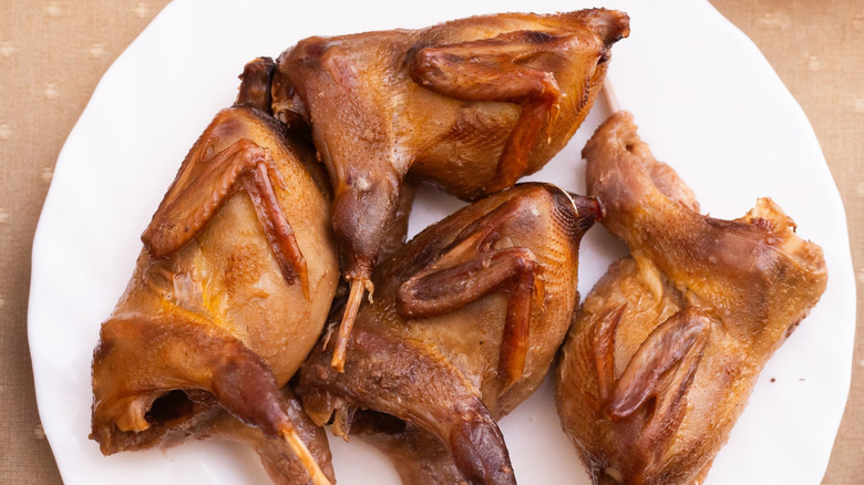 Four whole, cooked small game birds on a white plate