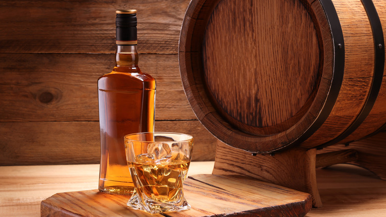 A bottle of whiskey and a barrel
