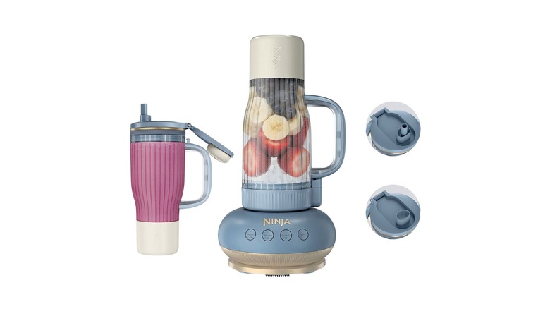 Blender with extra tumbler and two lids against a white background.