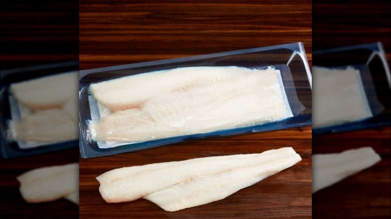 A package of raw Kirkland Signature Pacific cod on a wooden board