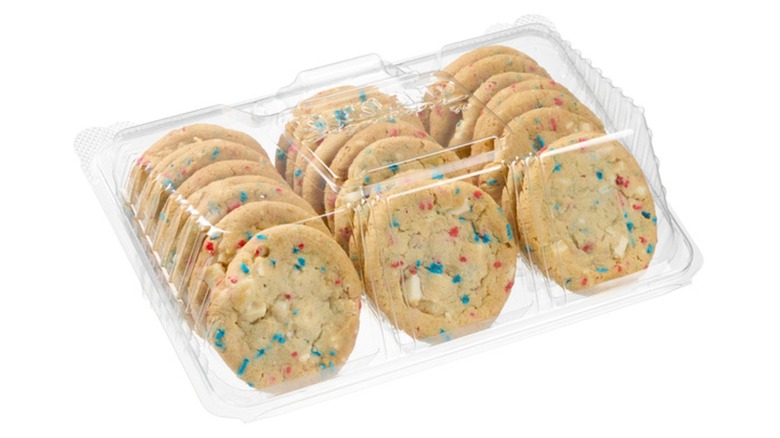 A clear box of sugar cookies dotted with red and blue sprinkles and white chocolate chips