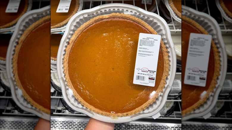 A hand holding a Costco pumpkin pie