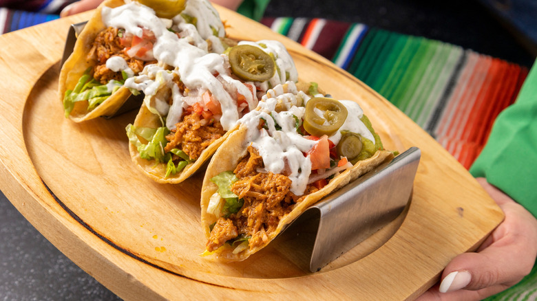 Pulled chicken tacos are served on a wooden tray
