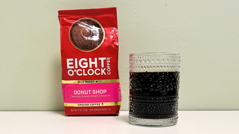 A glass cup filled with coffee next to a bag of Eight O Clock Coffee Donut Shop blend