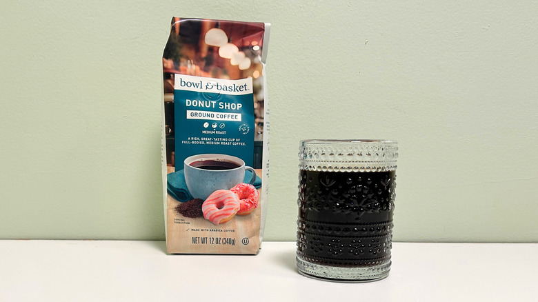 A glass cup filled with coffee next to a bag of Bowl and Basket Donut Shop Ground Coffee