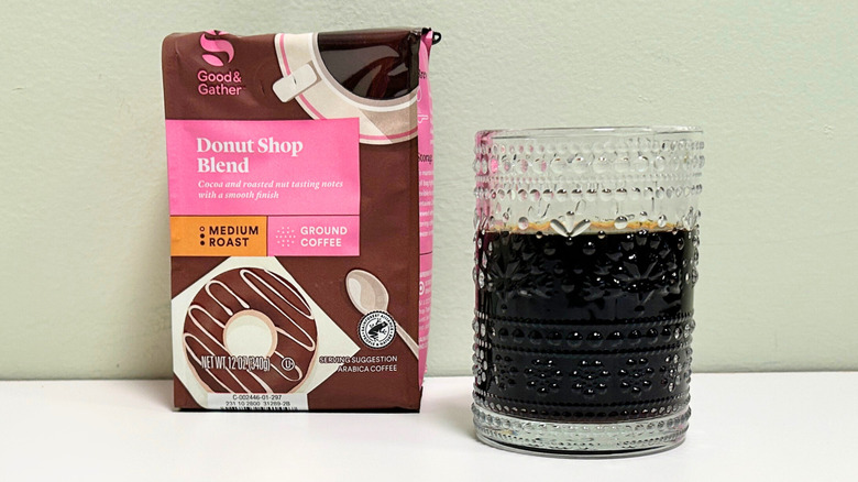 A glass cup filled with coffee next to a bag of Good and Gather Donut Shop Blend
