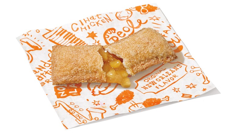 A split-open Popeyes Cinnamon Apple Pie on a white background