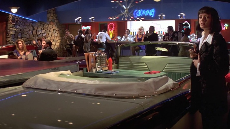 Pulp Fiction character Mia Wallace, played by Uma Thurman, standing beside a car booth in Jack Rabbit Slim's