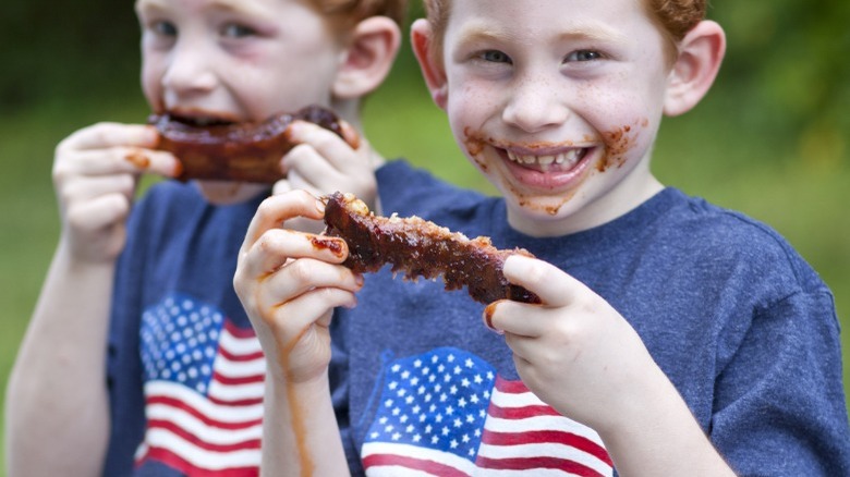 Twin boys eating ribs