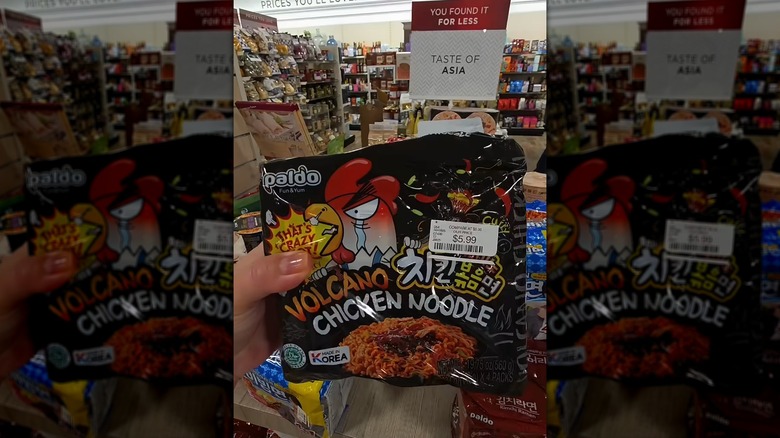 A hand holding a pack of Volcano Instant Chicken Noodles at HomeGoods