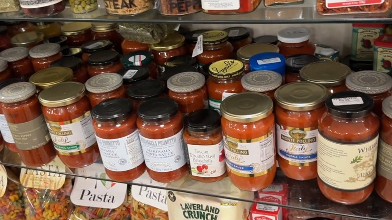 Jars of red pasta sauces on a glass shelf
