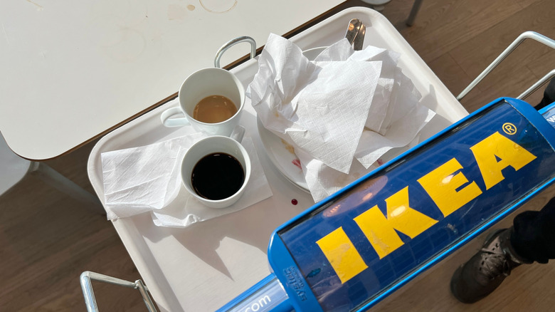 A tray in an IKEA food court, showing finished cups of tea, coffee, and plates of food