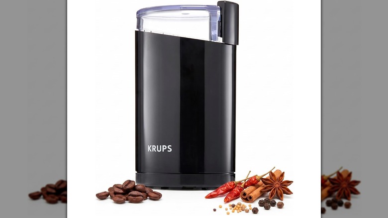 An electric coffee grinder with coffee beans on a white background
