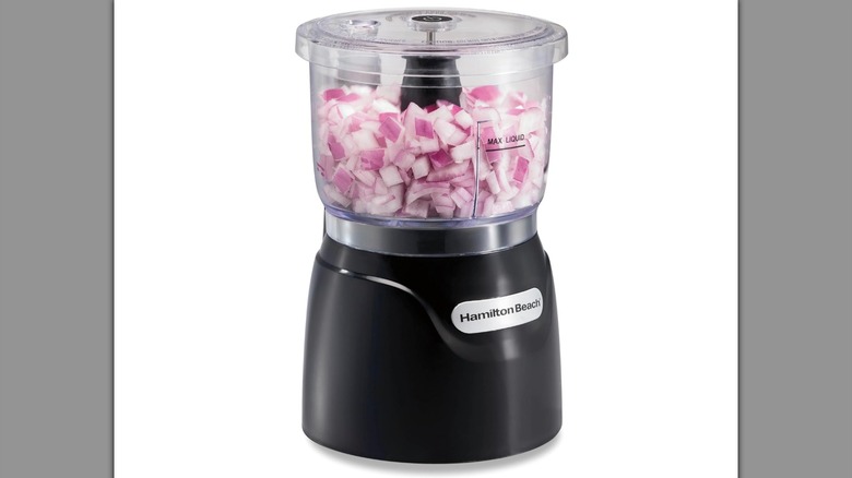 Mini food processor filled with onions on a white background