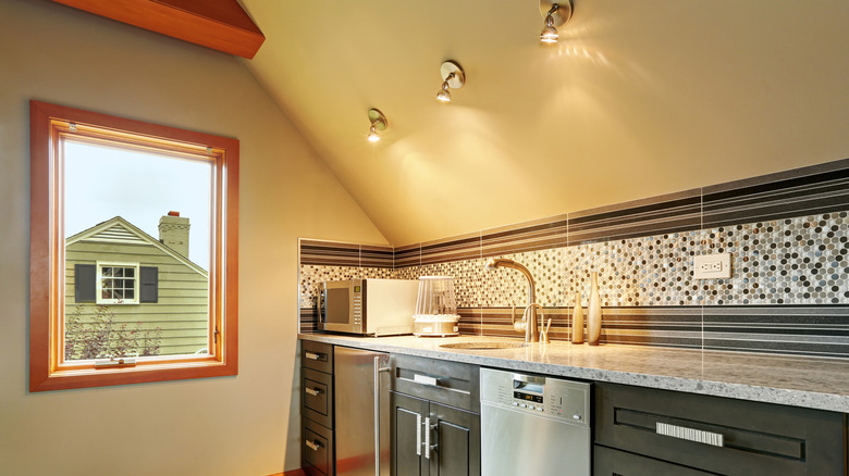 A modern kitchen with a cherry wood-colored window frame looking outside