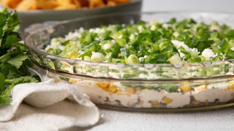 crumbly white cheese with green onions and corn in a clear pie plate