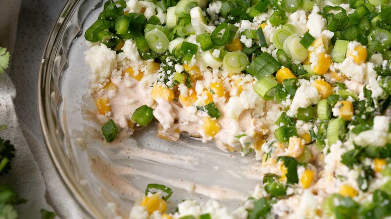 crumbly white cheese with green onions and corn in a clear pie plate