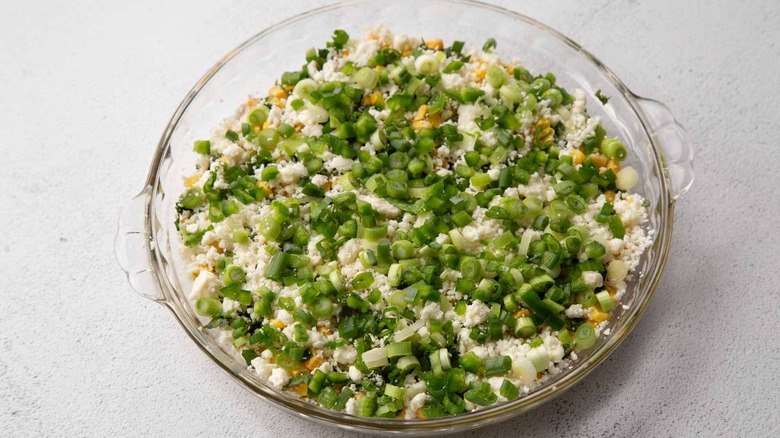 crumbly white cheese and green onions in a clear pie plate