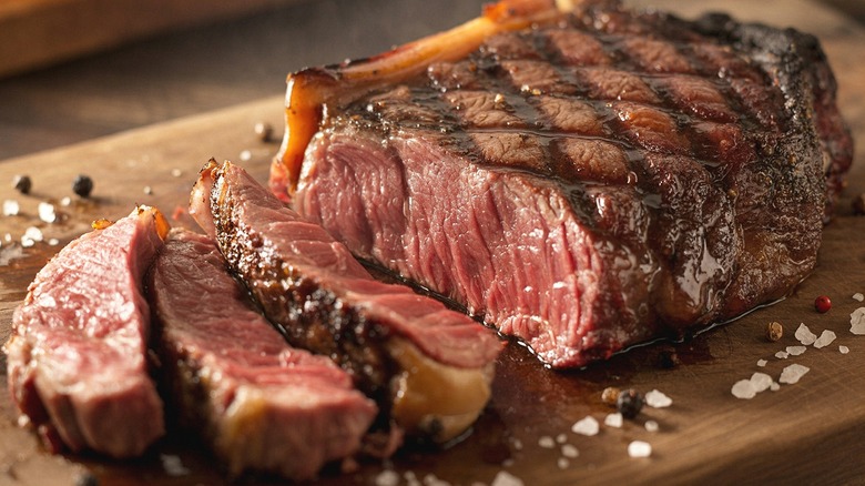 A medium to rare juicy steak, sliced with salt flakes and pepper corn