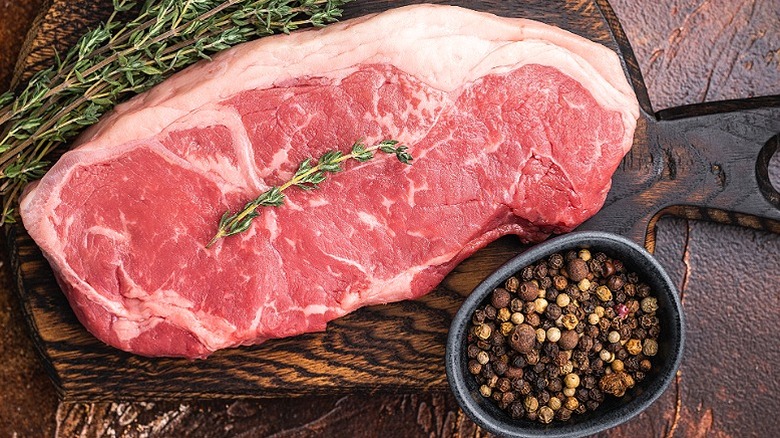 Raw New York strip beef steak on a wooden board.
