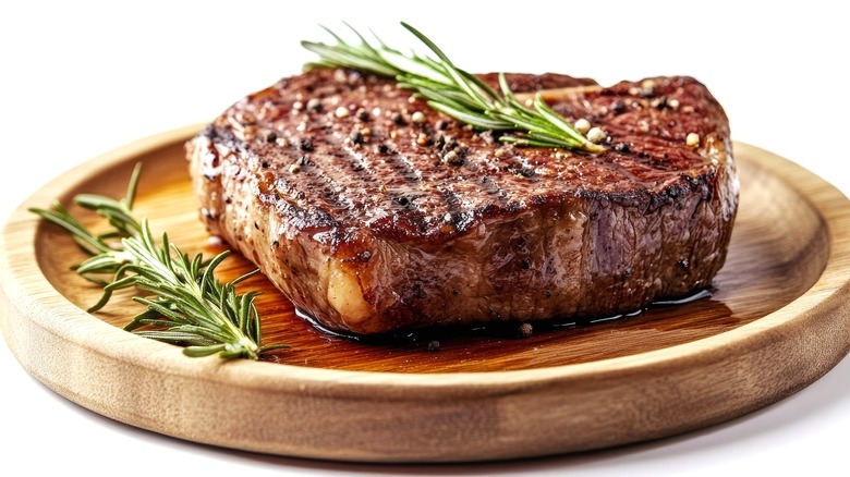 Grilled Steak with Rosemary on Wooden Plate